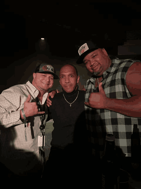 three men are posing for a picture and one of them is wearing a hat that says coca cola