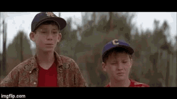 two young boys wearing baseball caps with the letter c on them are standing next to each other .