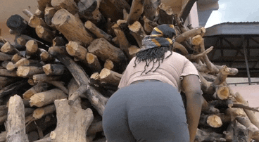 a woman standing in front of a pile of wood