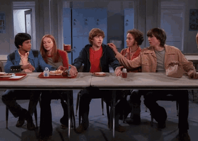 a group of people sit at a table with a tray of food and a bottle of water