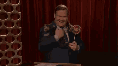 a man in a suit and tie is holding a lollipop in his hand .