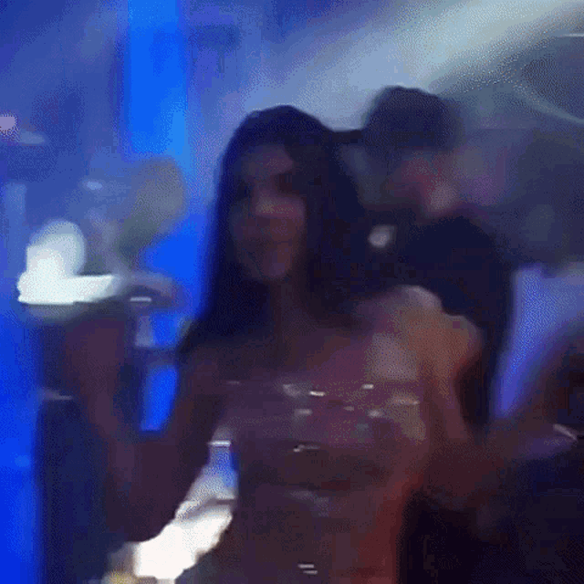 a woman in a pink dress is dancing in a dark room .