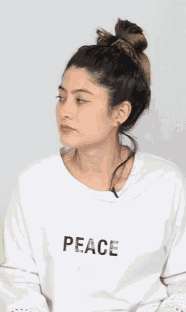 a woman is wearing a white shirt that says peace on it