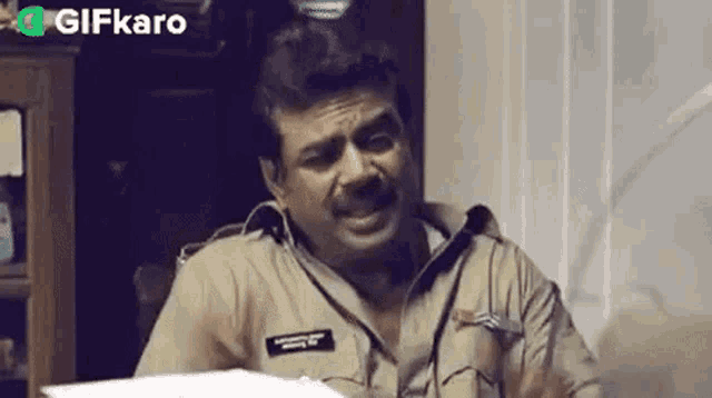 a man in a police uniform is sitting at a desk with a piece of paper .