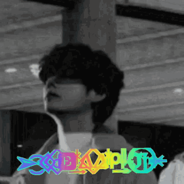a black and white photo of a young man with a rainbow colored logo .