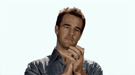 a man in a blue shirt is clapping his hands and looking at the camera .