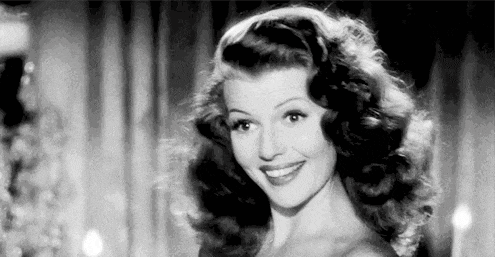 a black and white photo of a woman smiling and looking at the camera .