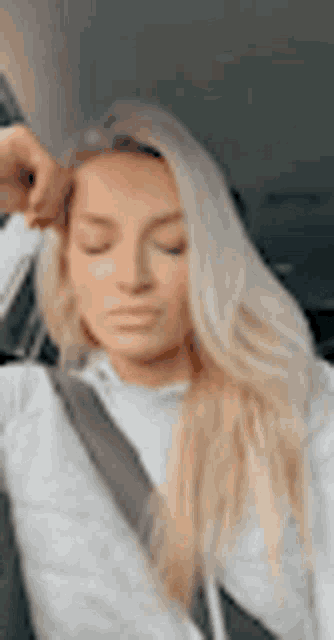 a woman is sitting in a car with her eyes closed and a seat belt on .