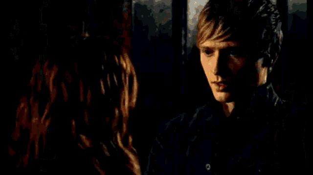 a man and a woman are standing next to each other in a dark room with a lamp in the background .