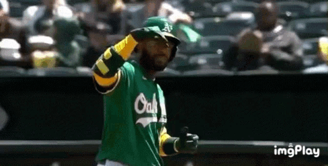 a baseball player wearing a green and yellow uniform is standing on the field .