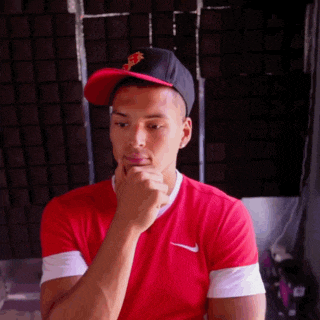 a man wearing a red nike shirt and a black hat is thinking