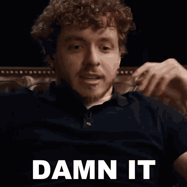 a man with curly hair is sitting in a chair and says damn it