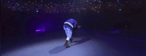 a man in blue shorts is kneeling on a stage in front of a crowd