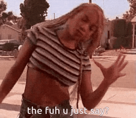 a woman in a striped crop top and shorts is standing on a sidewalk and says the fuh u just say ?