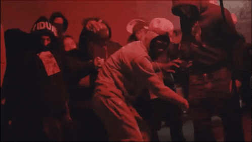 a group of people are dancing in a dark room with a man wearing a hoodie that says " ido " on it