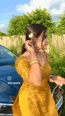 a woman in a yellow dress is putting a flower in her ear