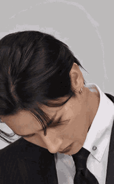 a man in a suit and tie is looking down at something .