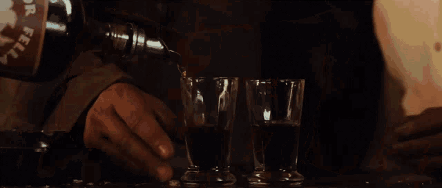 a man is pouring a drink into a shot glass while wearing gloves .