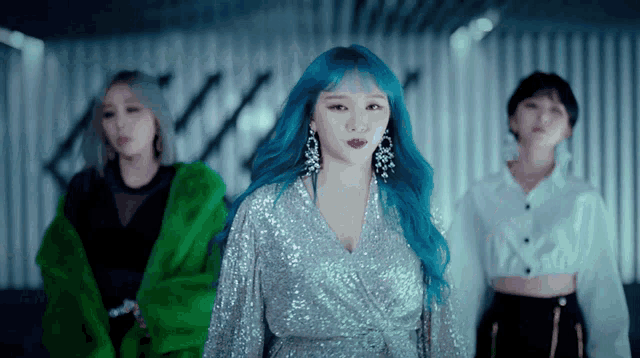 a woman with blue hair and earrings is standing in front of two other women