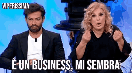 a man and a woman are sitting next to each other and the woman is saying e un business mi sembra
