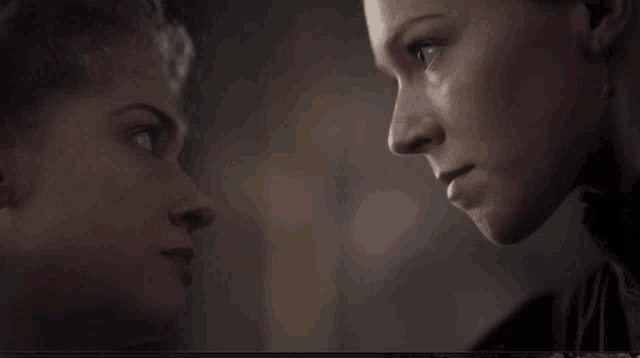 two women are looking at each other in a dark room .