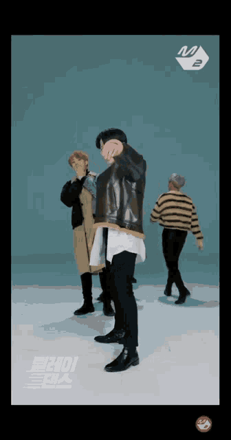a group of young men are dancing in front of a blue background with the letters m and b on it