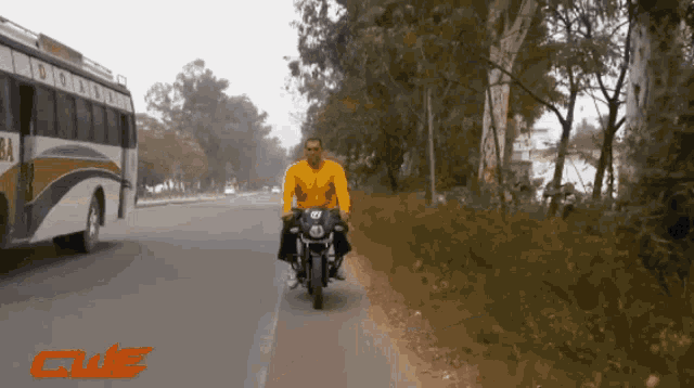 a man is riding a motorcycle down a road with a bus in the background and the word clue in red