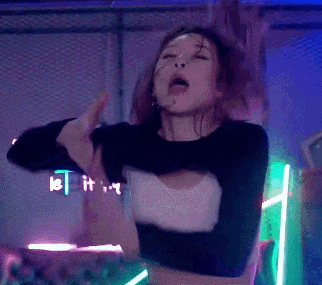a woman is dancing in front of a neon sign that says let it .