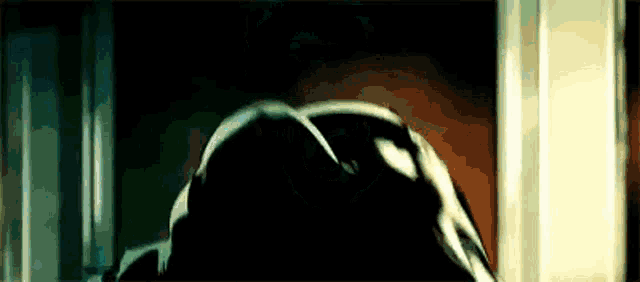 a person is standing in a dark room in front of a window .