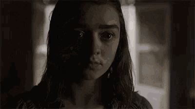 a close up of a woman 's face in a dark room with a window in the background .