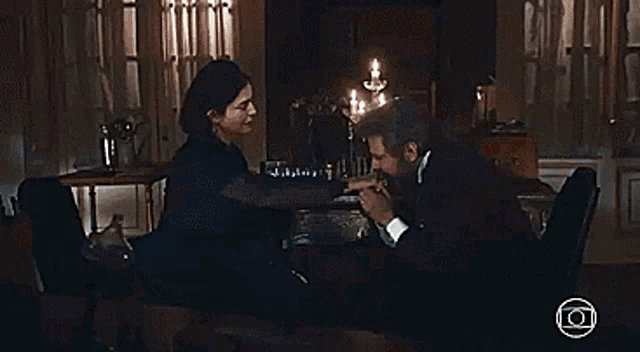 a man and woman are sitting at a table holding hands .