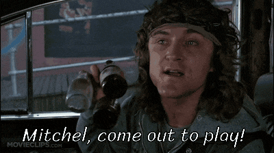 a man in a car is holding two bottles of beer and says mitchel come out to play