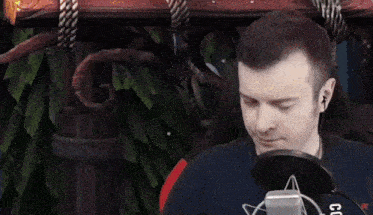 a man wearing headphones is sitting in front of a microphone and holding a red object .