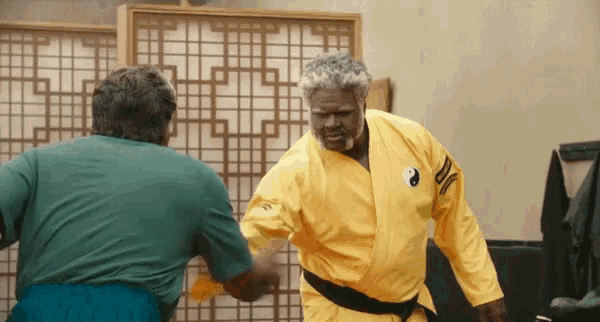 a man in a yellow karate uniform has a yin yang symbol on his shoulder