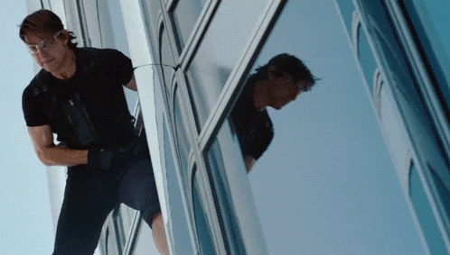 a man in a black shirt is climbing up a tall building