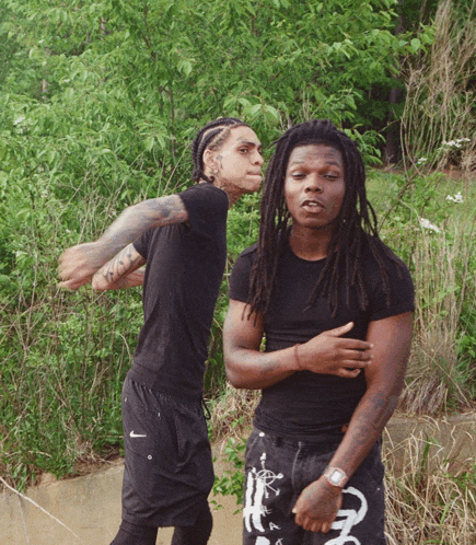 a man with dreadlocks is standing next to another man in a black shirt