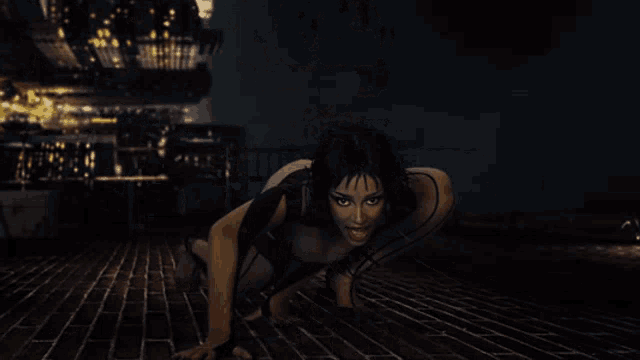 a woman in a black bodysuit is crawling on the ground