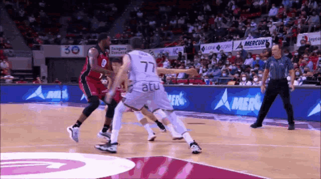 a basketball player with the number 77 on his jersey tries to get past another player
