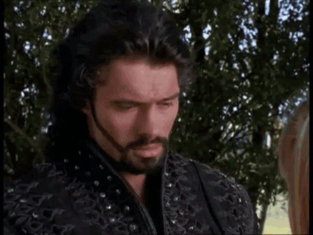 a man with a beard is talking to a woman and says " what 's that "
