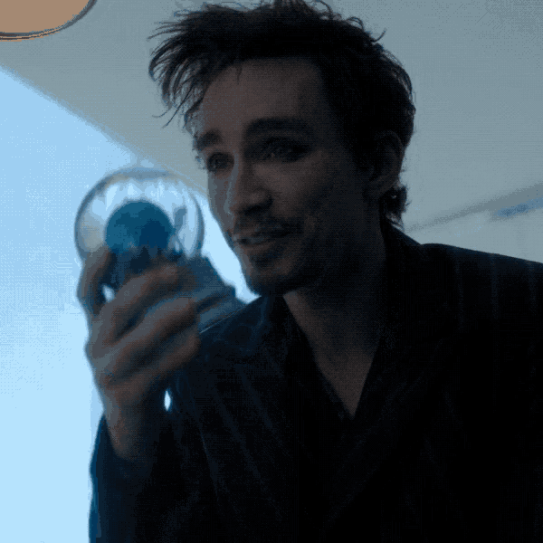 a man is holding a snow globe with a blue globe inside of it