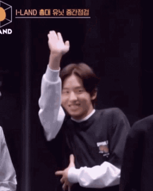 a man in a black shirt is raising his hand in the air while smiling .