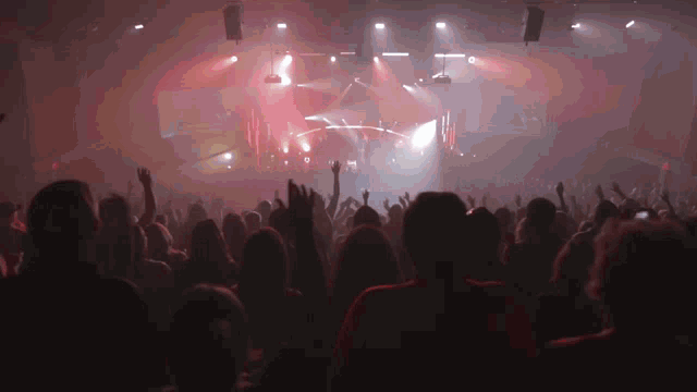 a crowd of people watching a concert with their hands in the air