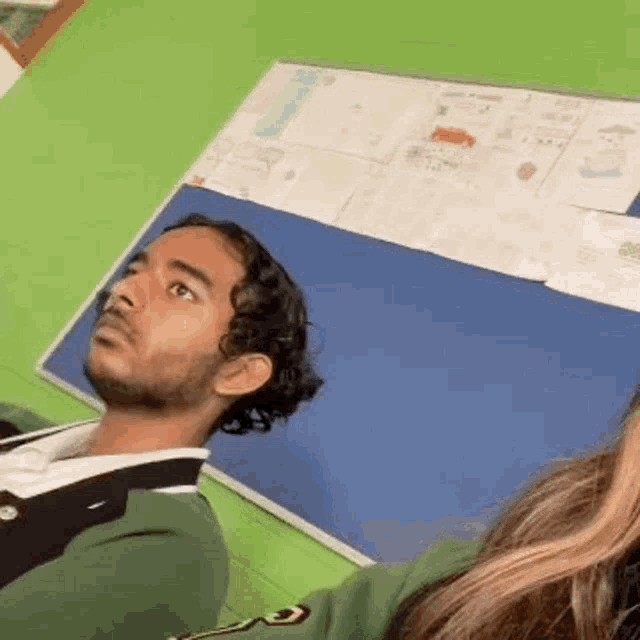 a man and a woman are sitting in front of a blue board in a classroom .