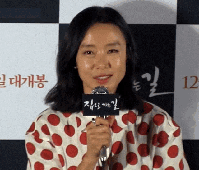 a woman in a polka dot shirt holds a microphone