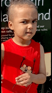 a young boy in a red tank top is standing in front of a sign that says " keep our ren safe "