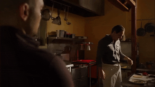 a man standing in a kitchen talking to another man who says you 're here right on time