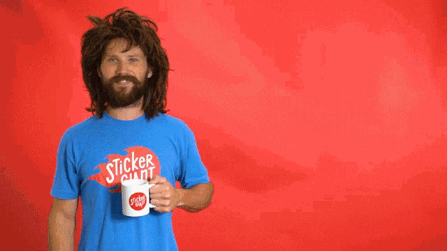 a man wearing a blue shirt that says sticker mart holds a cup of coffee