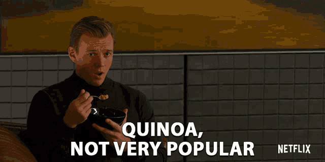 a man is holding a bowl of food and says " quinoa not very popular " on the bottom