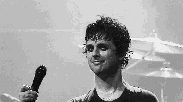 a black and white photo of a man holding a microphone on stage .