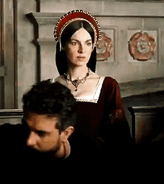a woman wearing a red and gold headdress stands next to a man